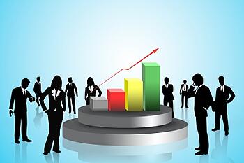 Business team considering management decisions standing around a bar chart Business team considering management decisions standing around a bar chart