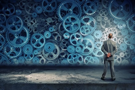 Back view of businessman looking at cogwheel mechanisms of predictive modeling.jpeg Back view of businessman looking at cogwheel mechanisms of predictive modeling.jpeg