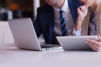 business strategists contemplating market demand analysis on laptop computer